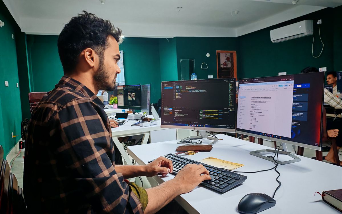 A developer working on code at a dual monitor setup