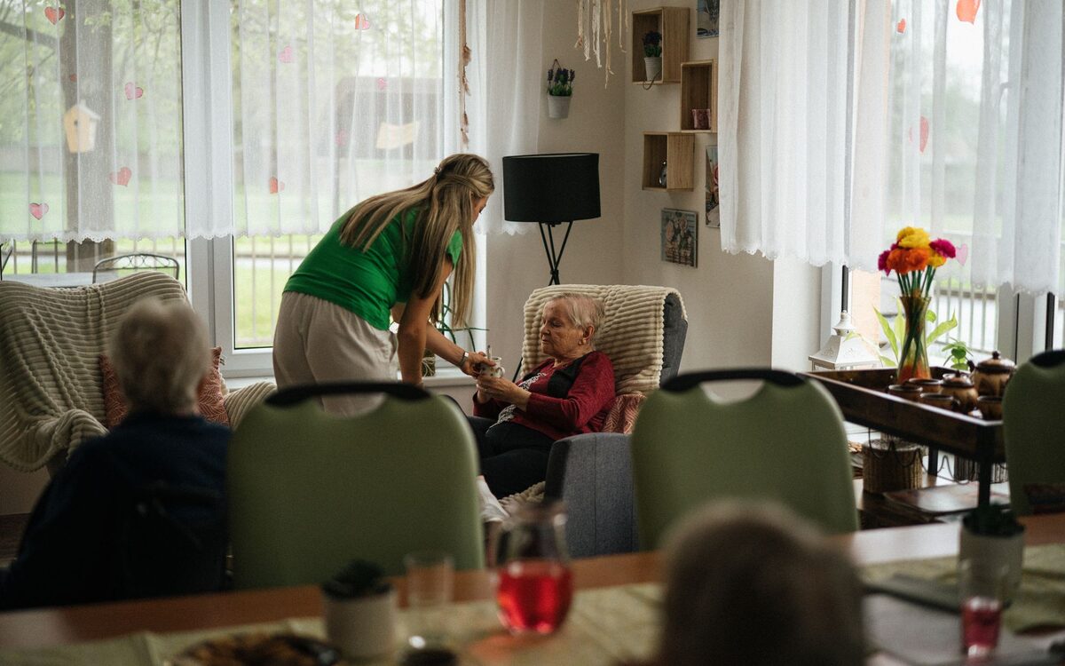 A carer sitting with residents in a care home lounge