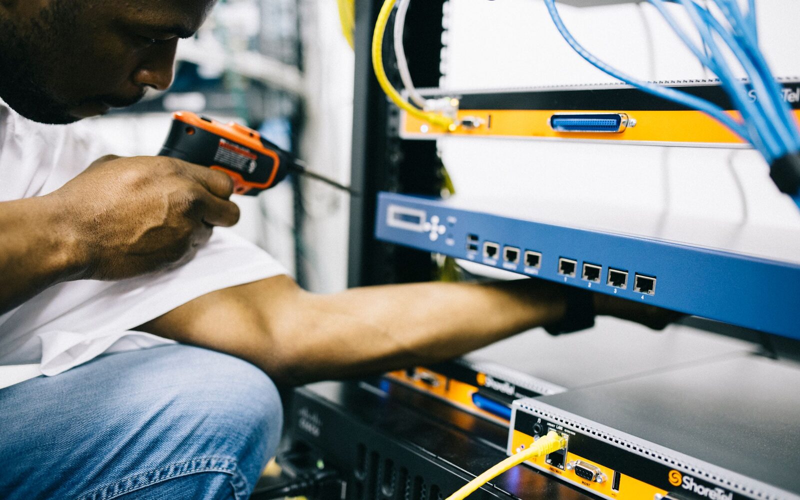An engineer working inside a network cabinet with a screwdriver