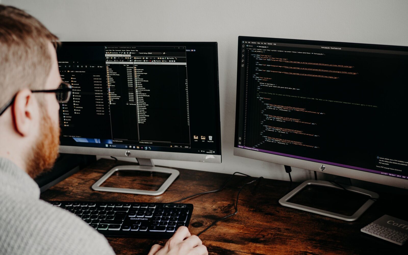 A developer working on code across two monitors