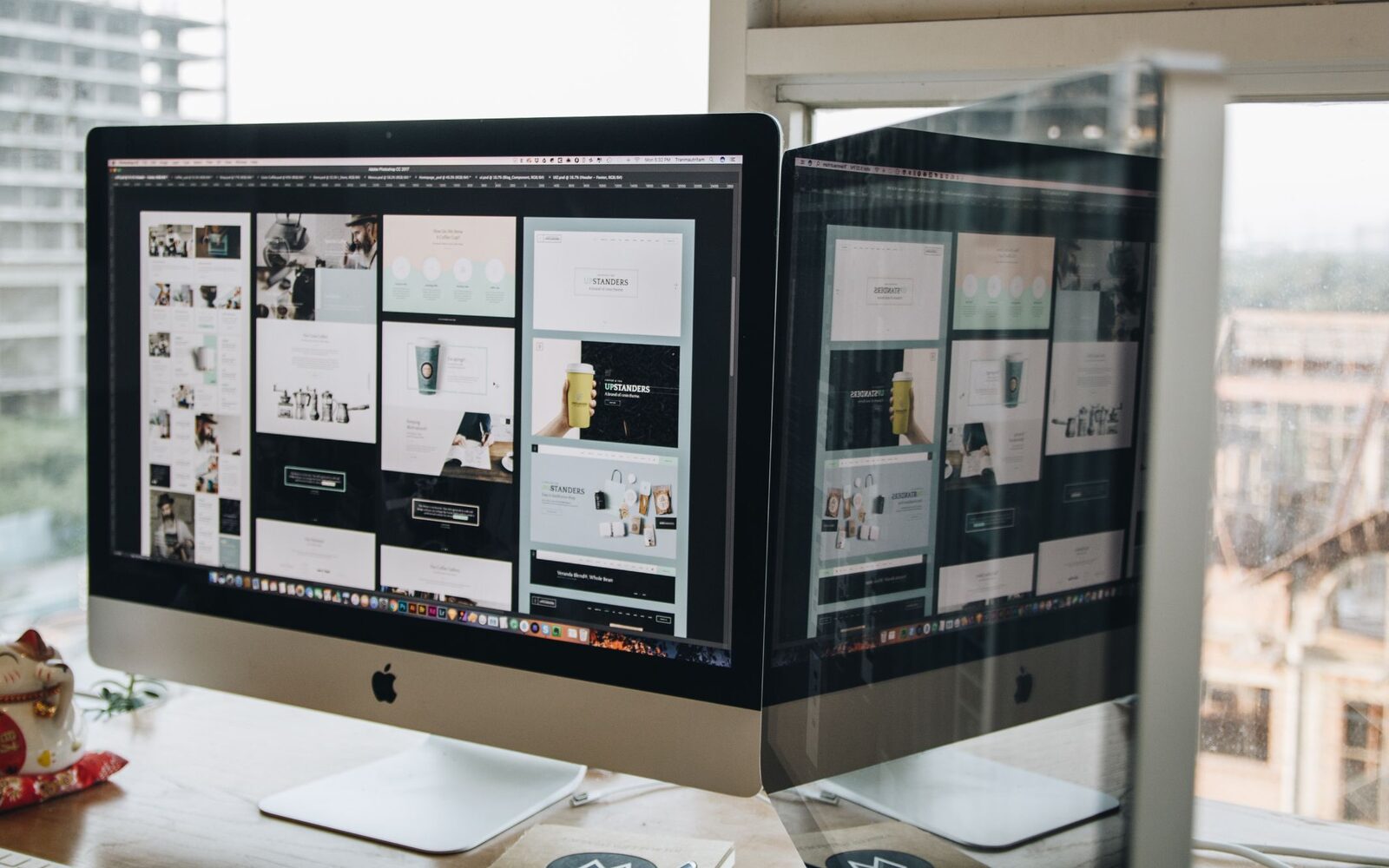 Two monitors showing web page layouts being worked on